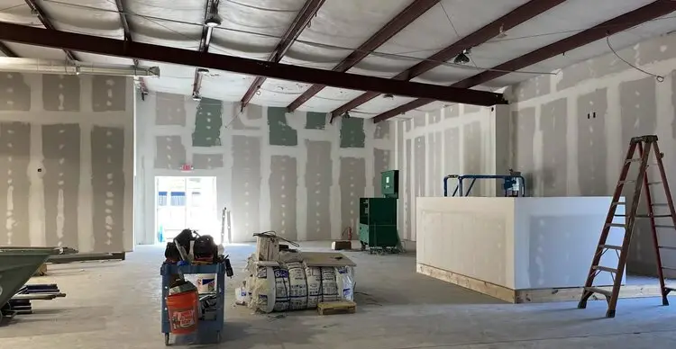 Commercial interior build-out with fresh drywall and steel roof framing