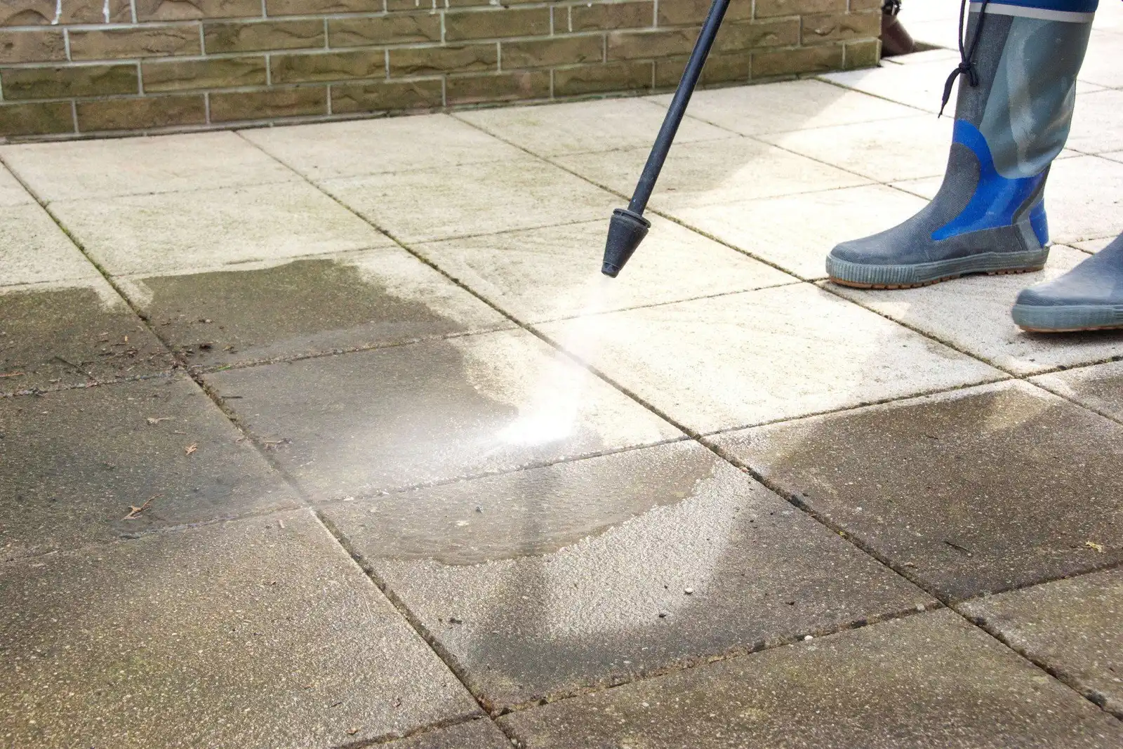 Pressure washer cleaning a dirty concrete sidewalk, clean stripe showing